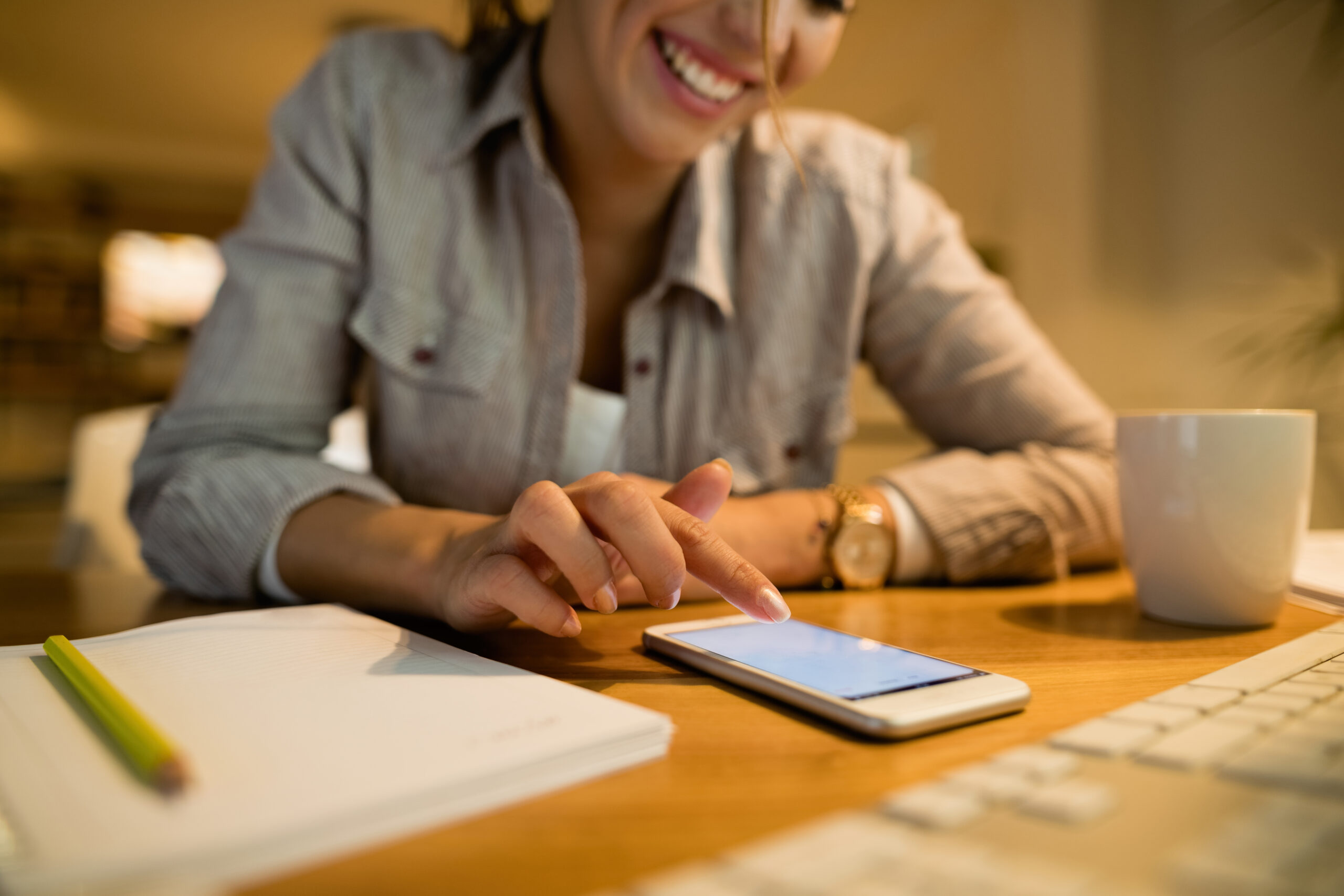 Close-up of happy woman texting on smart phone at home.